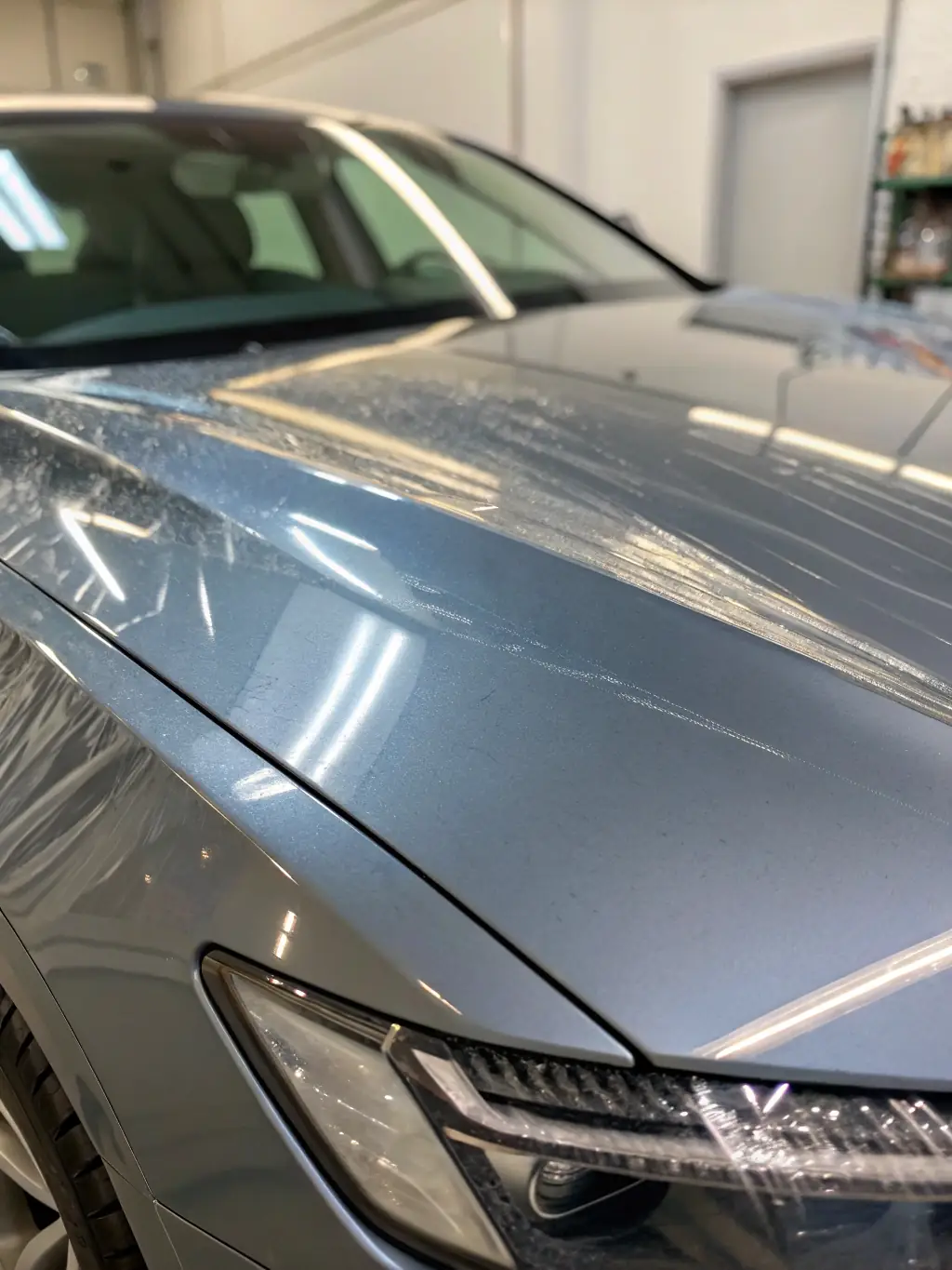 Close-up of a car's hood with clear, glossy Paint Protection Film (PPF) showing its self-healing properties after minor scratches, installed by Chicago Auto Spa.